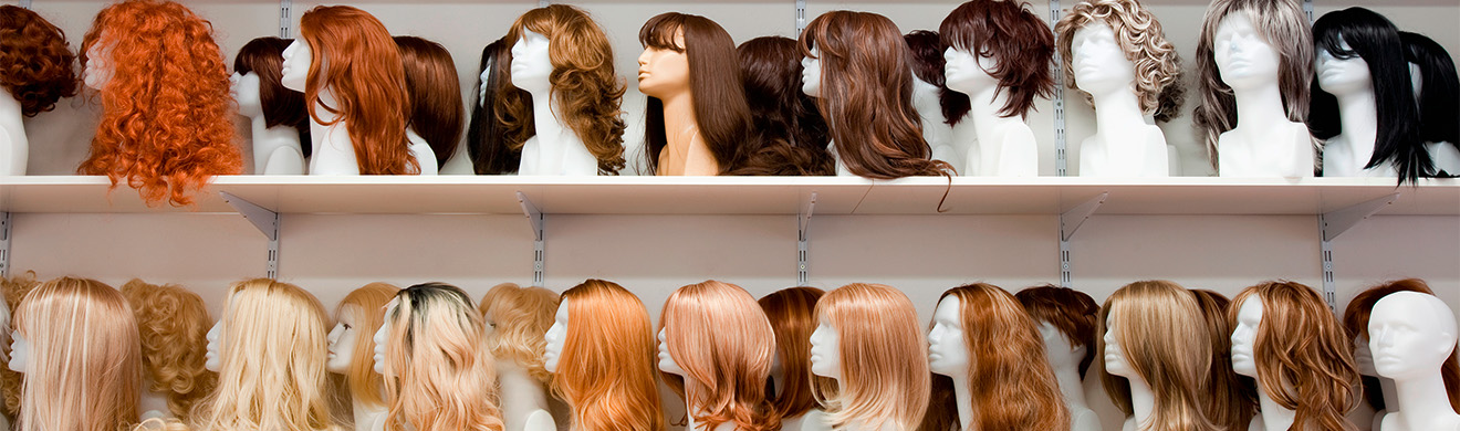 Reihe von Schaufensterköpfen mit Perücken in einem Fachgeschäft für Zweithaar – Vielfalt an Frisuren.