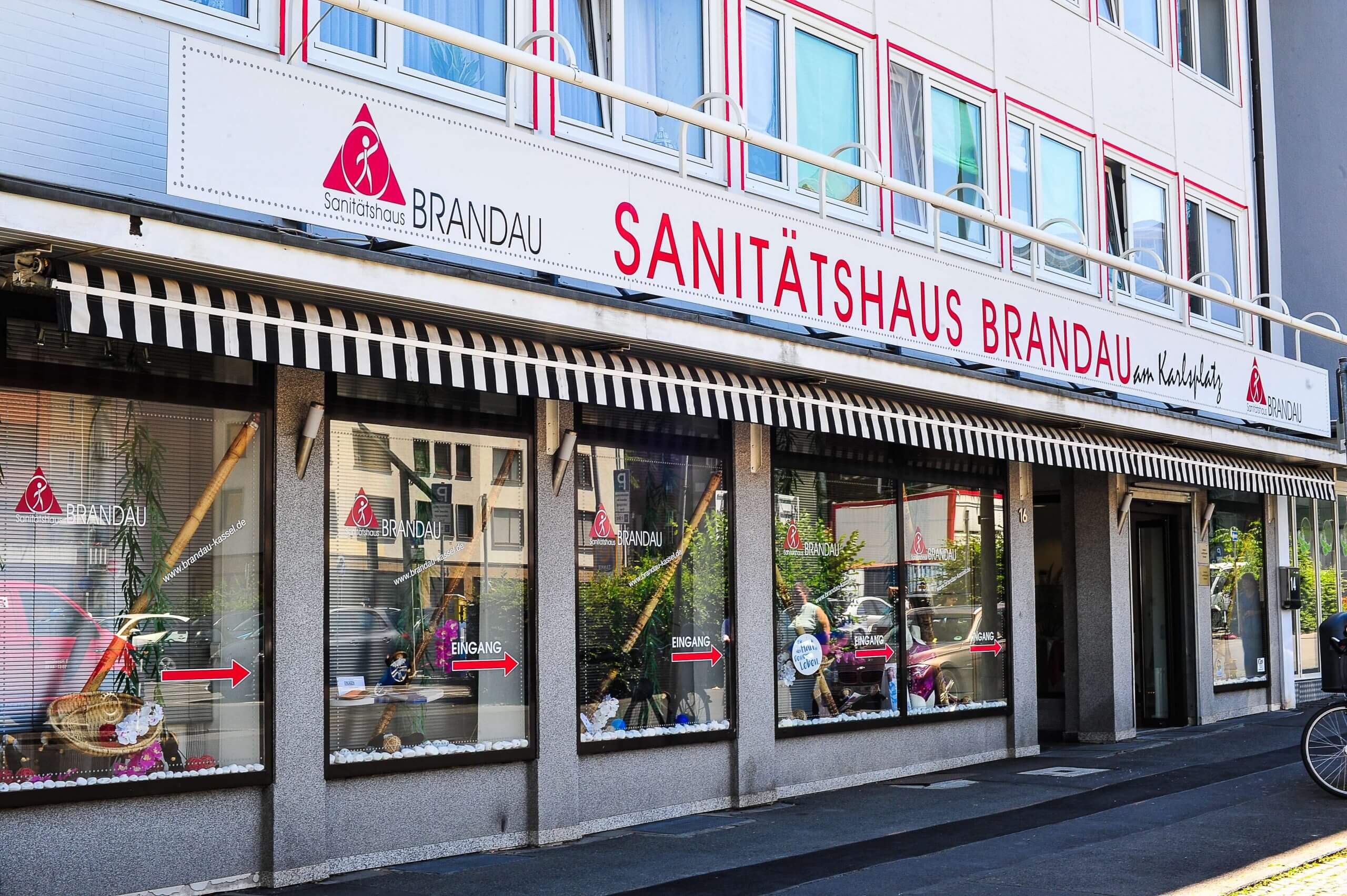 Außenansicht Sanitätshaus Brandau am Karlsplatz Kassel mit Schaufenstern und Eingangsbereich, zeigt Fachgeschäft für medizinische Hilfsmittel und Beratung.
